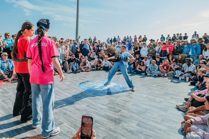 Battle : une danseuse en jean dans le cercle, face à deux danseuses du Maroc, devant la foule