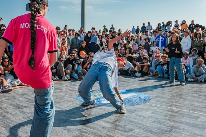 Une danseuse plonge au sol au centre du cercle, maillot du Maroc au premier plan