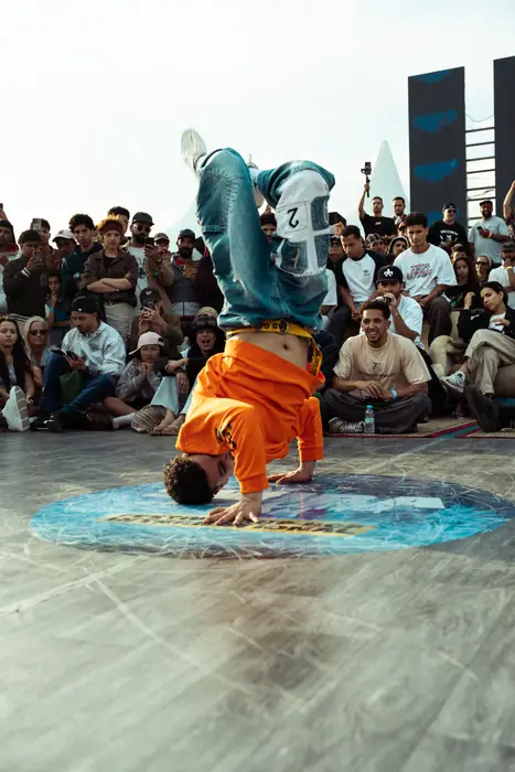 Un danseur en orange tourne sur la tête