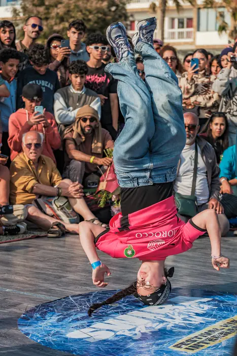 Une jeune danseuse en équilibre sur la tête au milieu du public