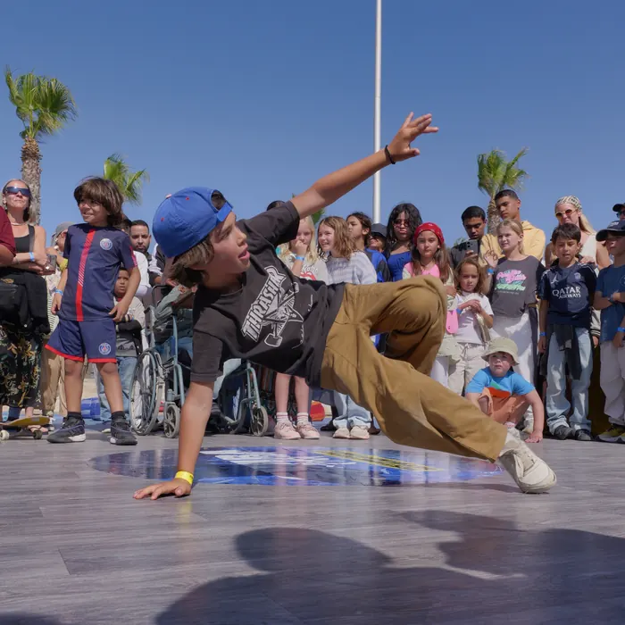 Un jeune danseur à casquette bleue en plein mouvement devant les enfants
