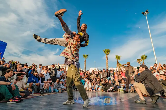 Un danseur s'envole au-dessus du cercle, devant la foule de la corniche