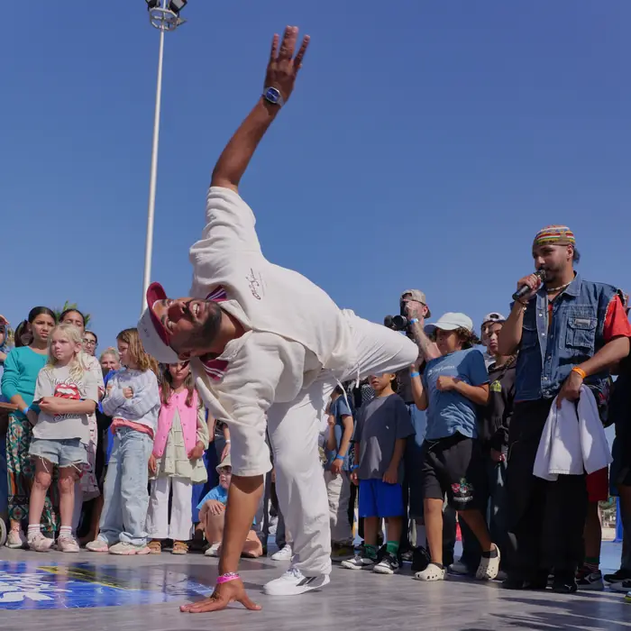 Un danseur en blanc saute devant des dizaines d'enfants